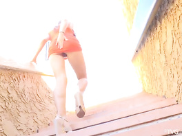 Sweetie in orange sexy dress hotly masturbates pussy on stairs outdoors